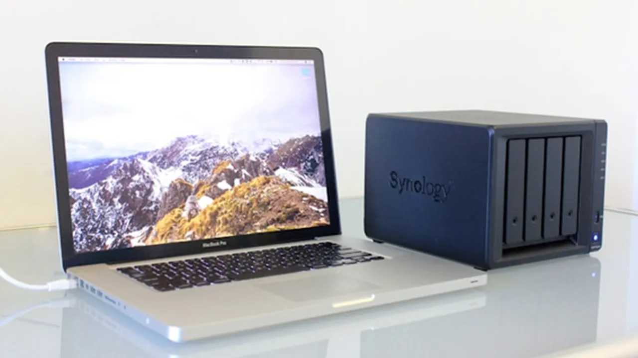 Portátil conectado a un dispositivo NAS de Synology sobre una mesa.